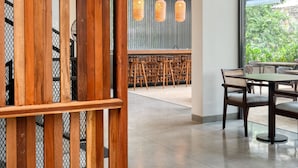 A modern interior with a wooden partition, a bar area with stools, and a seating area with tables and chairs. - Taprobane House (Colombo)