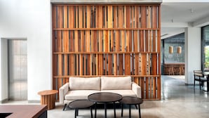 A modern interior with a wooden slatted wall, a sofa, and a coffee table. - Taprobane House (Colombo)