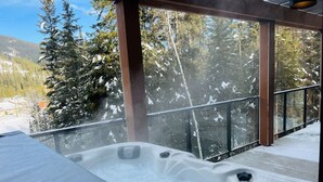 Una vasca idromassaggio con vista su alberi e montagne innevate.