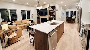 Una cucina moderna con isola centrale, mobili in legno, elettrodomestici in acciaio inossidabile e luci a sospensione.