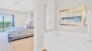 A bedroom with a large bed, a bathroom with a bathtub, and a balcony with a view. - Near Disney - Family Condo w Pool, Games, and More (Winter Garden)