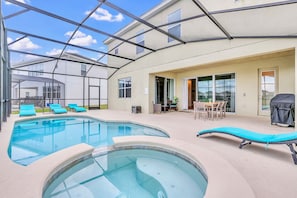 Piscina com espreguiçadeiras, banheira de hidromassagem e área de terraço coberta com mobiliário de exterior.