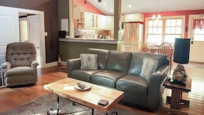 Un salon avec un canapé en cuir, une table basse en bois et un fauteuil gris.