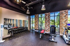 Un gimnasio con equipo de ejercicio, ventanas amplias y un diseño de pared de ladrillo.