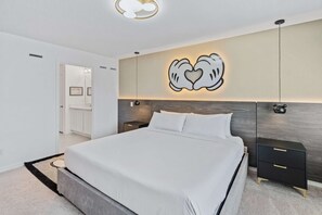 A modern bedroom with a large bed, a bedside table, a wall-mounted light, and a decorative wall piece. - Disney Dreams: 3BR Mickey Theme Townhouse w/ Patio (Davenport)