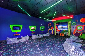 A room with neon lights, multiple screens, and patterned seating. - Disney Dreams: 3BR Mickey Theme Townhouse w/ Patio (Davenport)