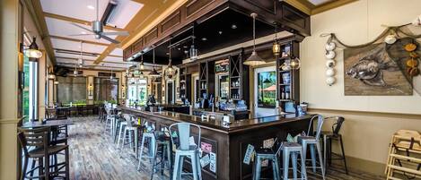 A bar area with a counter, stools, and a mural of fish on the wall.