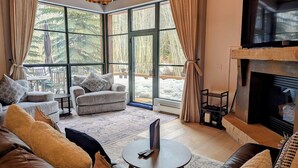 A spacious living room with a fireplace, large windows, and comfortable seating.