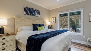 A bedroom with a bed, bedside tables, a window with a view, and a ceiling fan.