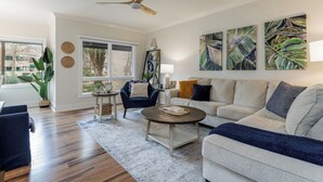 A living room with a sofa, armchairs, a coffee table, and artwork on the wall.