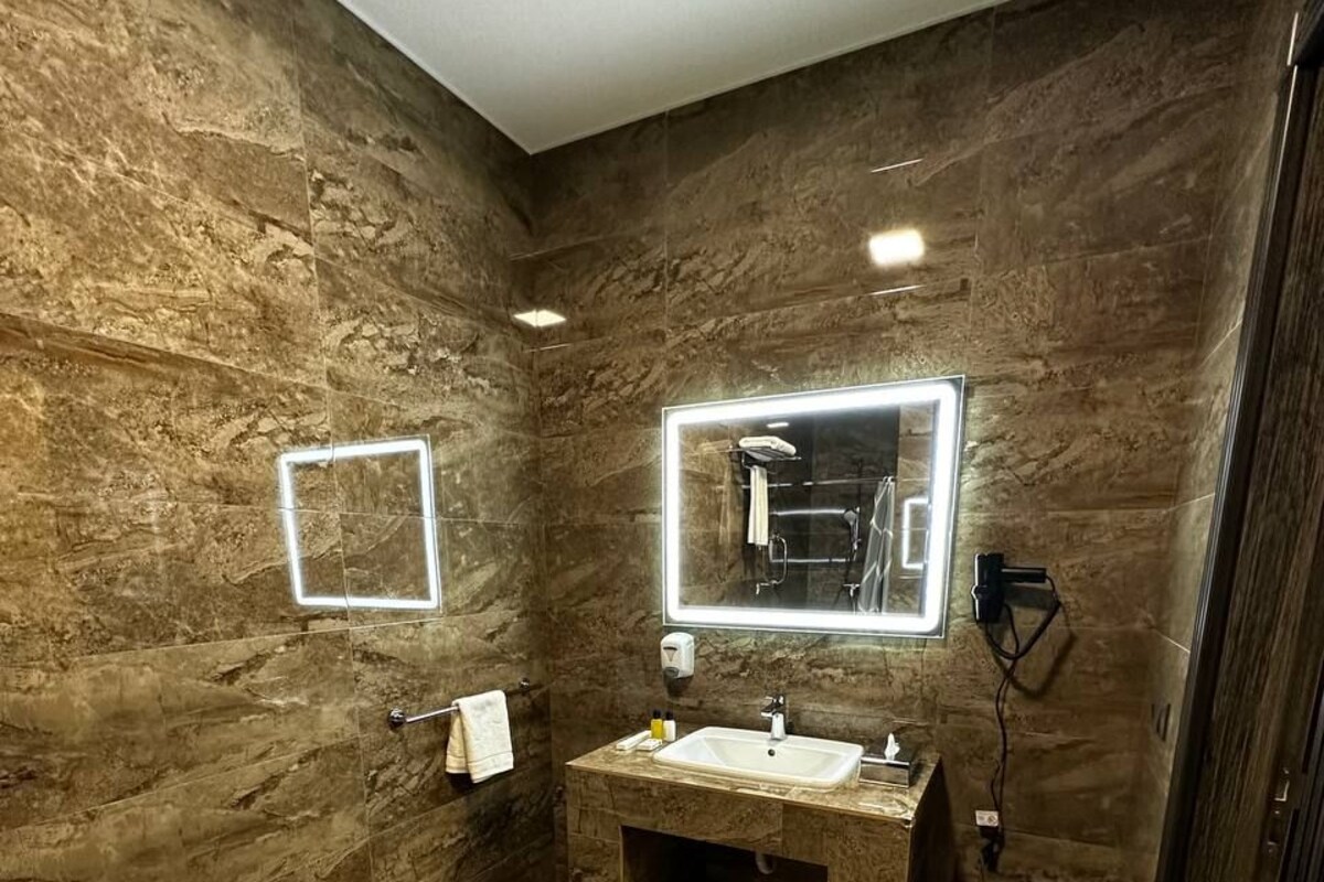 Casa de banho moderna com parede de mármore, um espelho grande, uma pia e um porta-toalhas.