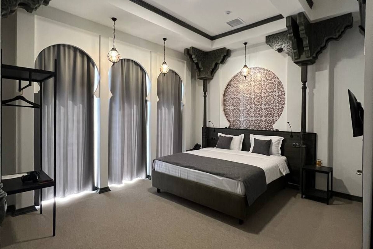 Um quarto moderno com uma cama grande, uma parede redonda com padrão e uma TV em um suporte.