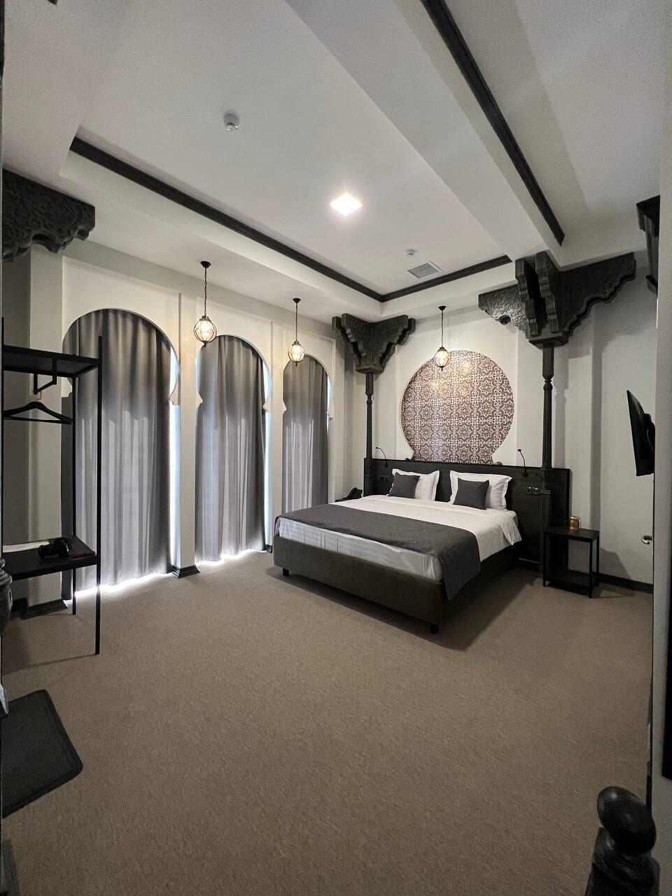 Un dormitorio moderno con una cama grande, un cabecero redondo con diseño y un televisor sobre un mueble.