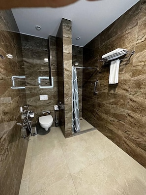 A modern bathroom with a shower, toilet, and sink, featuring marble walls and a tiled floor. - RASODA HOTEL AND RESTAURANT (Tashkent)