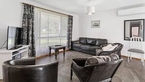 Ein modernes Wohnzimmer mit einer Couch, einem Sessel, einem Fernseher und einem kleinen Tisch.