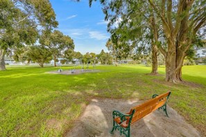 A park with a bench, trees, and a playground.