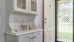 Ein weißer Schrank mit Glastüren, eine rosa Schale und ein kleines Regal mit Dekoration.