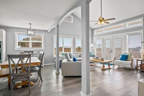A spacious living area with a dining table, chairs, a sofa, and a ceiling fan. - `Find me where the sand meets the sea at S.S. Minnow!  Welcome aboard S.S. Minnow, a beautiful coastal retreat where the ocean sets you free. Perfect for the whole family!` (Port Aransas)