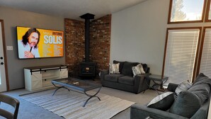 A living room with a fireplace, a sofa, a TV mounted on the wall, and a coffee table.