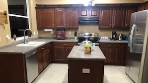 Una cocina con gabinetes de madera, un refrigerador de acero inoxidable, una estufa y un lavamanos.