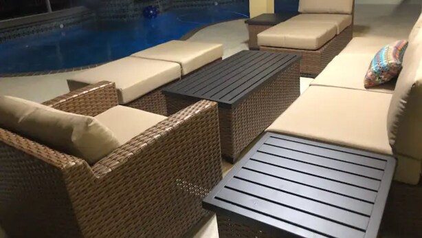 Un espacio al aire libre con mobiliario de mimbre y una piscina.