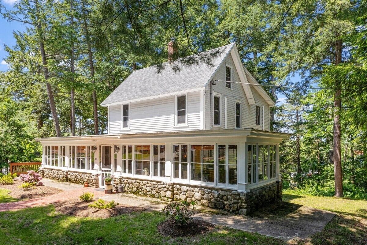 A two-story house with a covered porch and stone foundation.