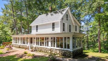 A two-story house with a covered porch and stone foundation.