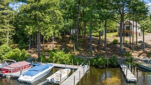 A lakeside property with docked boats, a house surrounded by trees, and a small dock area. - Vintage & Modern Lodge-Lake Winnipesaukee water access w/ boat slip, dog welcome (Gilford)