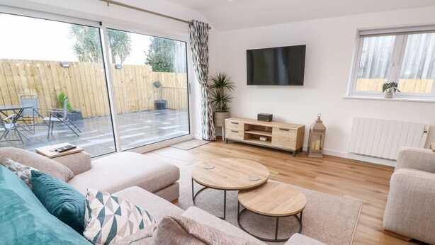 A modern living room with a sofa, two round tables, a TV, and a wooden cabinet.