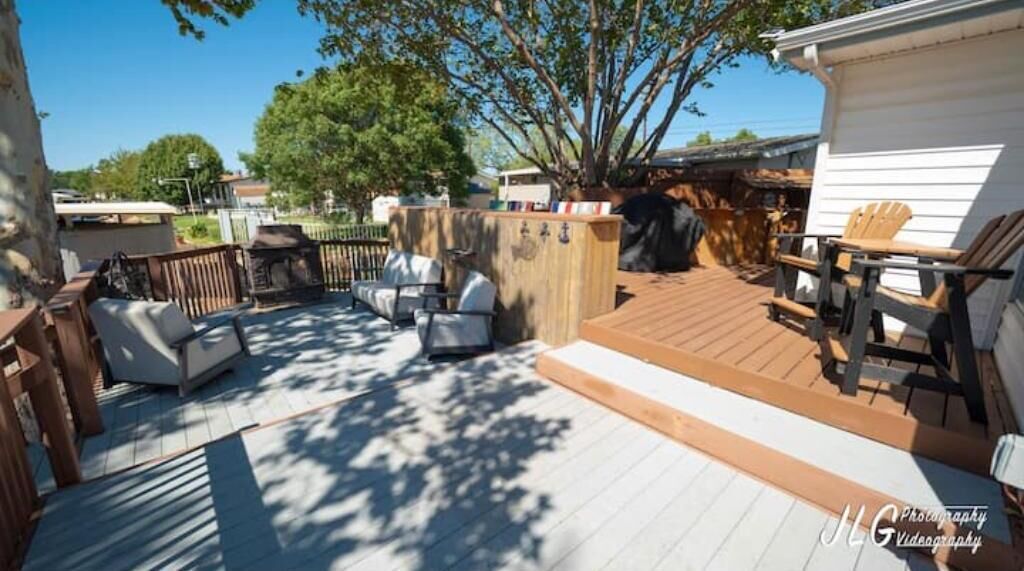 A wooden deck with outdoor furniture, a barbecue area, and a fenced garden.