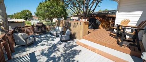 A wooden deck with outdoor furniture, a barbecue area, and a fenced garden.