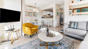 A modern living room with a sofa, a yellow armchair, a coffee table, and a flat-screen TV. - Villa HG21 Olympus - Two Bedroom Villa, Sleeps 4 (Kouklia)