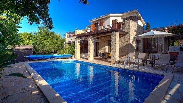 A swimming pool with a stone deck, a covered outdoor seating area, and a stone building with a balcony. - Villa HG21 Olympus - Two Bedroom Villa, Sleeps 4 (Kouklia)