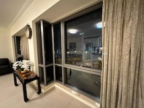 Relax in this stylish living room with a city view, featuring a sofa, side table, and vase of flowers.