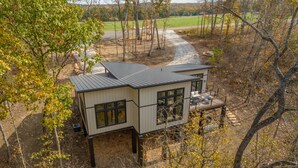 A modern two-story house with a metal roof, large windows, and a deck.