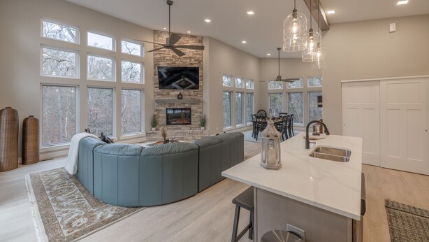 A spacious living room with a large L-shaped sectional sofa, a fireplace, and a dining area with a chandelier.