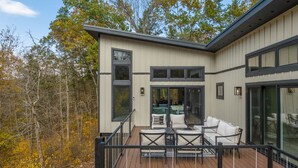 A modern house with a deck, outdoor furniture, and large windows.