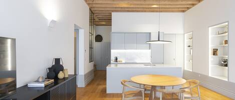 Una cocina moderna con armarios blancos, una isla central con asientos y suelo de madera.