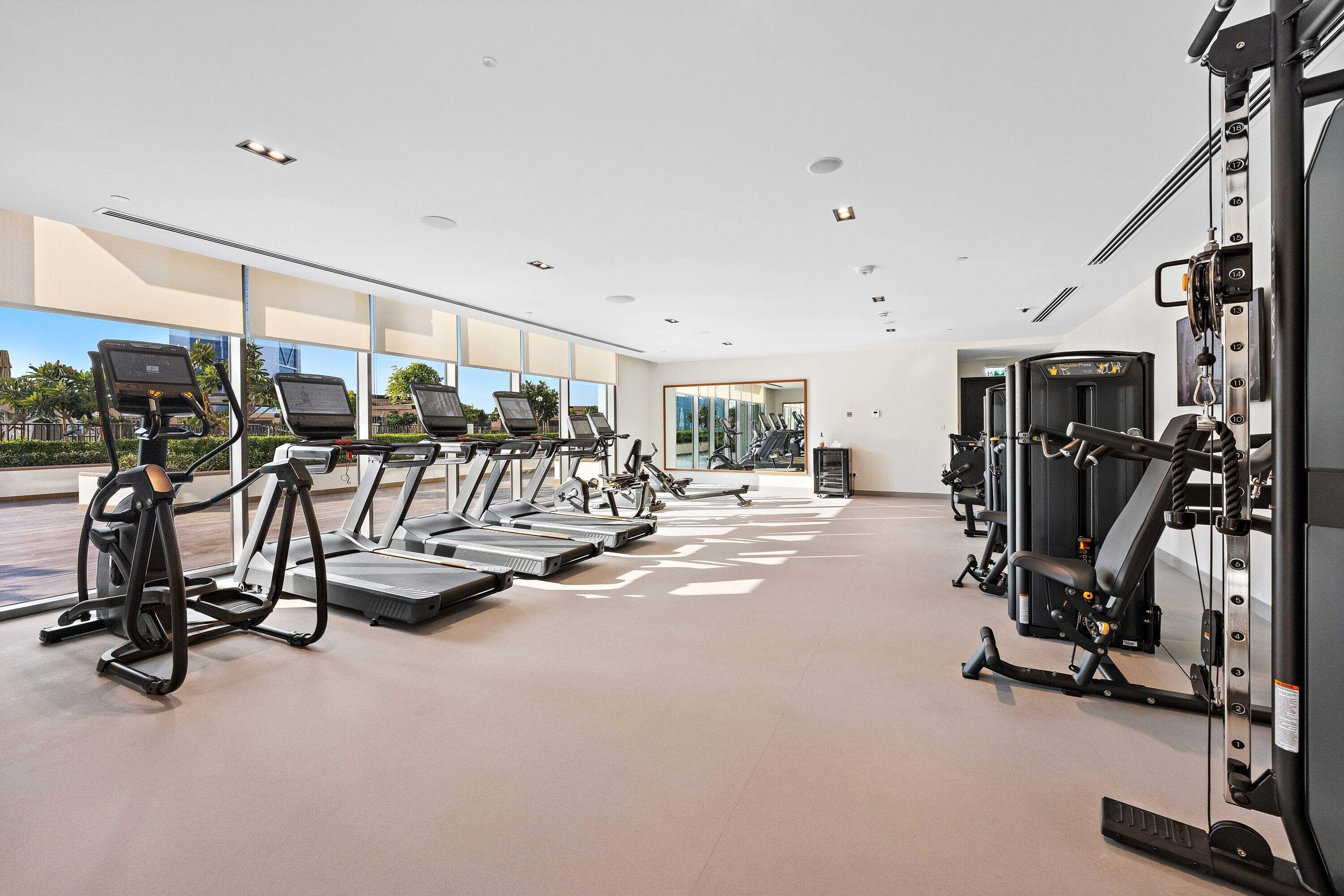A modern gym with treadmills, elliptical machines, and weightlifting equipment.