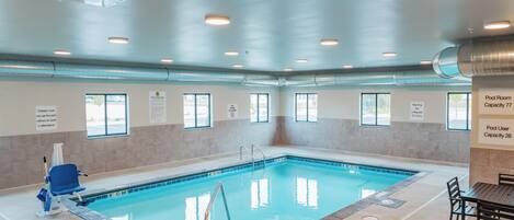 An indoor swimming pool with clear signage, including pool capacities and safety warnings.
