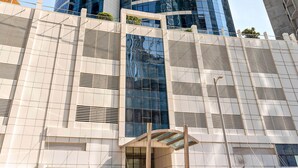 Un immeuble moderne de grande hauteur, doté d’une façade incurvée en verre et d’une série de fenêtres verticales.