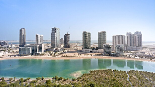 Un paysage urbain côtier avec de hauts immeubles, une plage et un ciel dégagé.