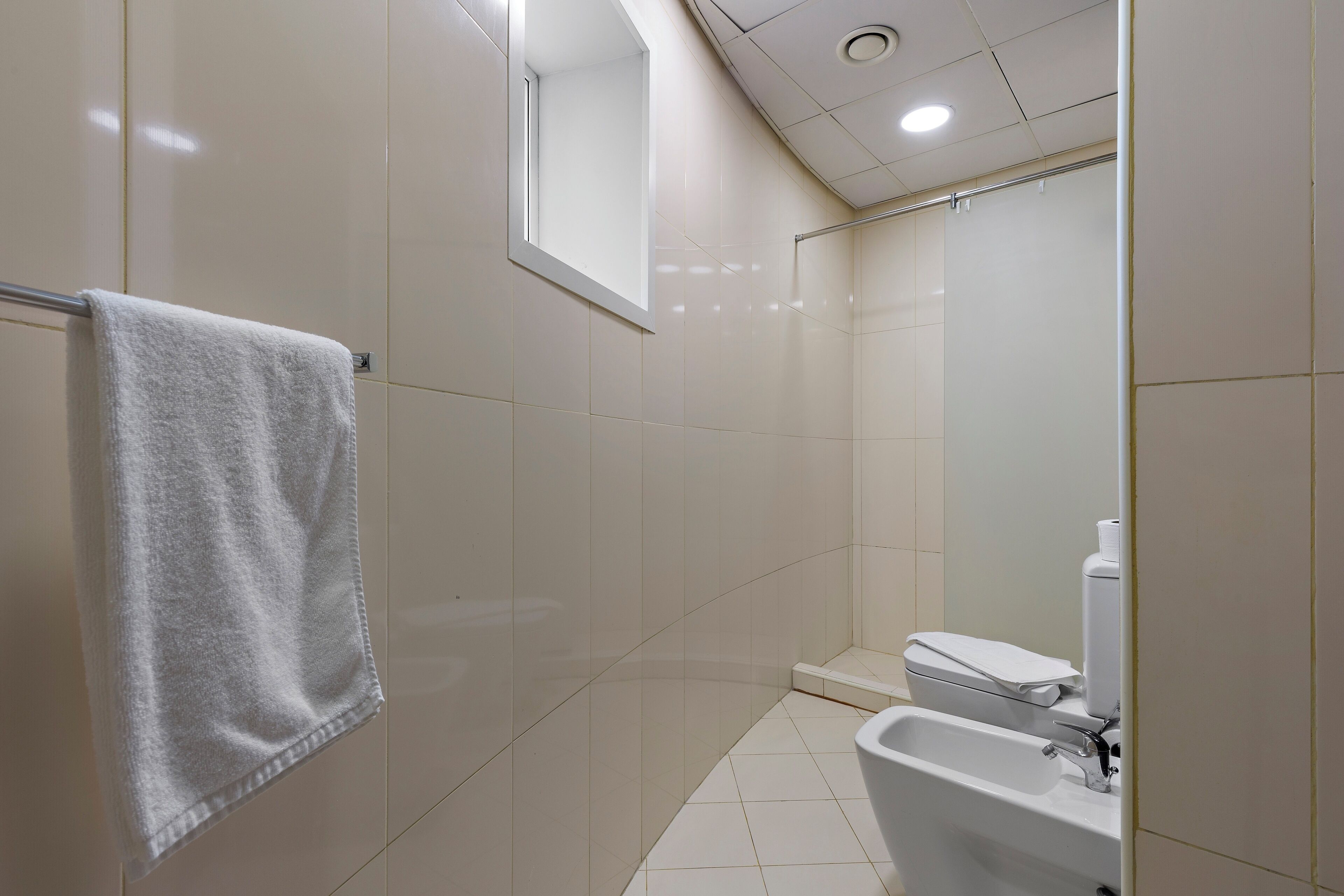 A bathroom with a white sink, toilet, and a towel hanging on a metal rack.