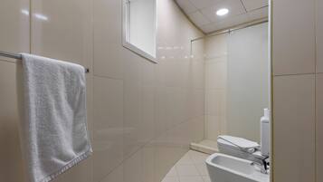 A bathroom with a white sink, toilet, and a towel hanging on a metal rack.