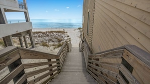 A wooden staircase leading to a beach with a clear view of the ocean.