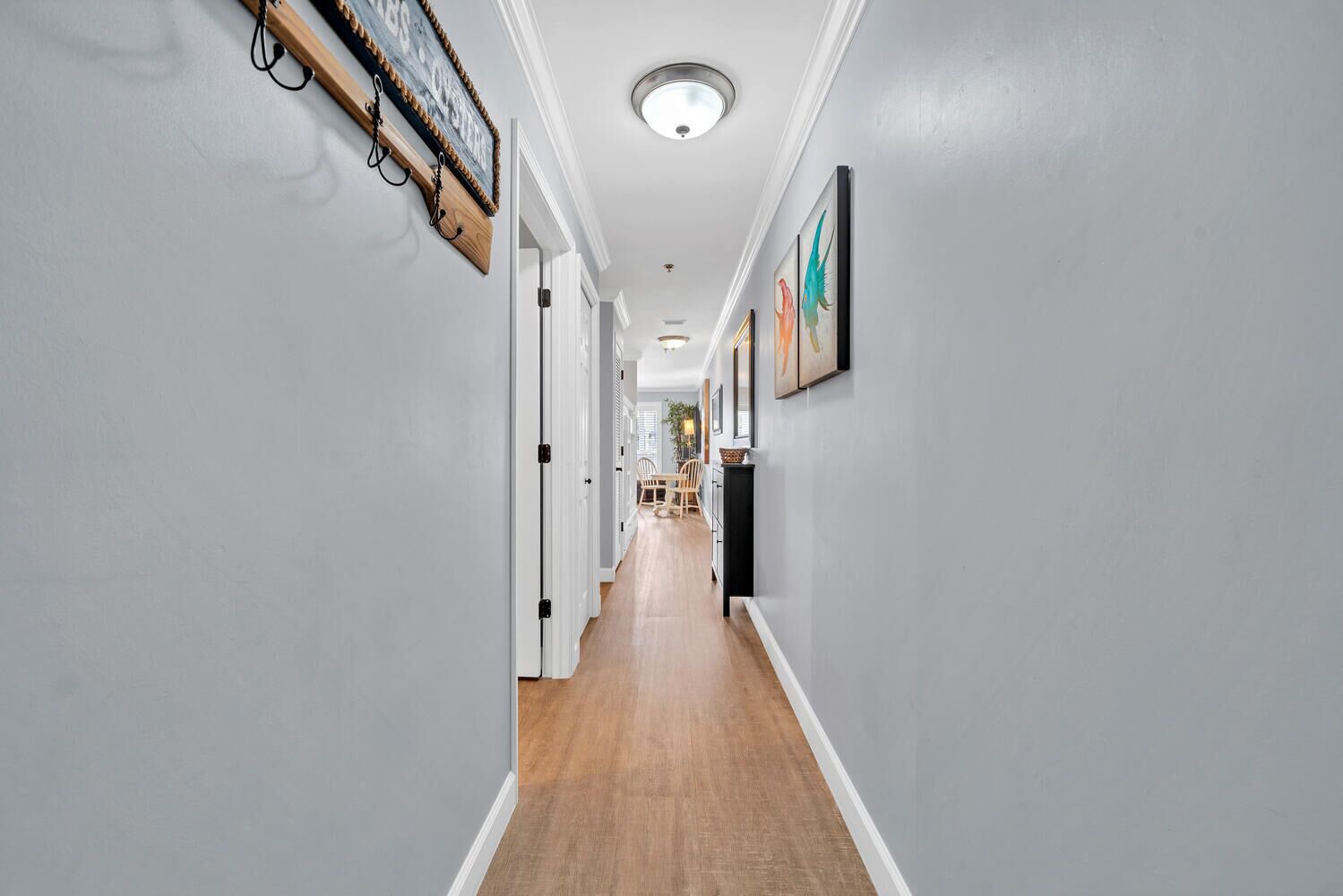 A hallway with light gray walls, wooden flooring, and a ceiling light fixture.