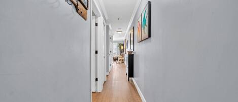 A hallway with light gray walls, wooden flooring, and a ceiling light fixture.