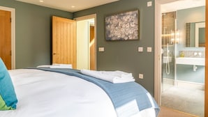 A bedroom with a bed, a bathroom with a shower, and a door leading to another room. - Little Hideaway - Four Bedroom Villa, Sleeps 8 (Whitelackington)