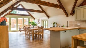 A spacious kitchen with wooden beams, a large island, and light-colored cabinets. - Little Hideaway - Four Bedroom Villa, Sleeps 8 (Whitelackington)