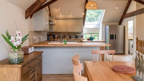 A modern kitchen with wooden beams, a central island, and a view to the outside. - Little Hideaway - Four Bedroom Villa, Sleeps 8 (Whitelackington)